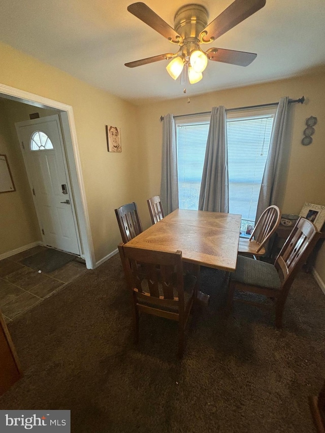 dining space featuring ceiling fan and dark colored carpet