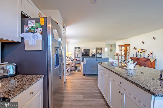 kitchen with light hardwood / wood-style floors, stone counters, white cabinetry, and stainless steel fridge with ice dispenser