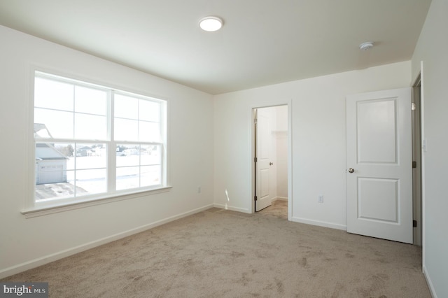 unfurnished bedroom featuring light colored carpet and a walk in closet