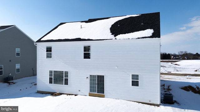 snow covered rear of property featuring central air condition unit