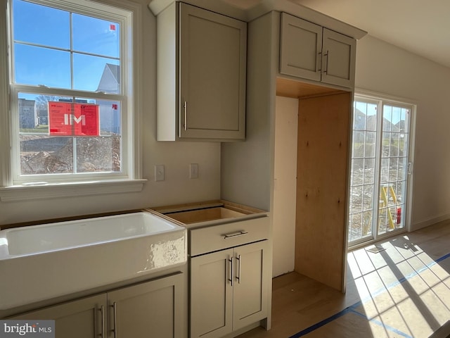 kitchen with gray cabinets, sink, and light hardwood / wood-style flooring