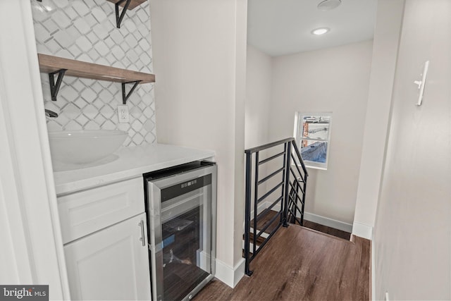 bar featuring white cabinetry, sink, dark hardwood / wood-style floors, beverage cooler, and decorative backsplash