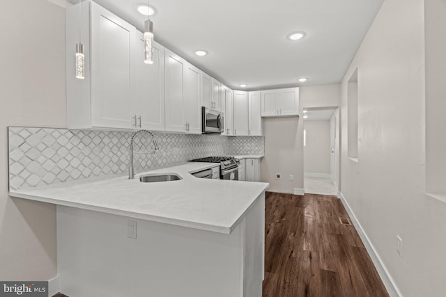 kitchen featuring white cabinetry, kitchen peninsula, appliances with stainless steel finishes, and hanging light fixtures