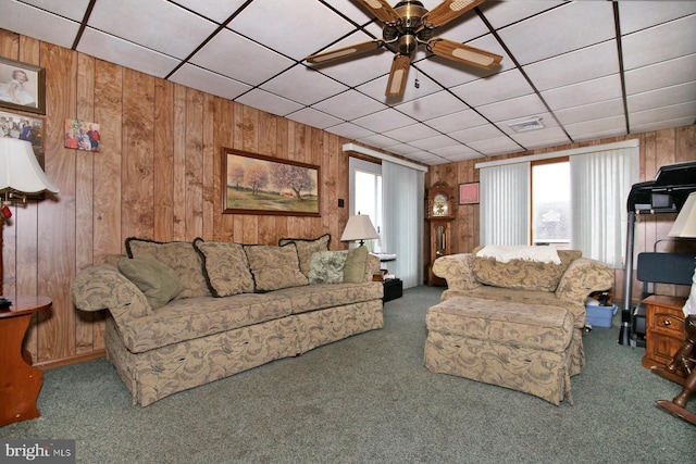 living room with carpet floors, ceiling fan, and wood walls