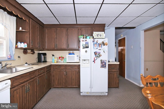 kitchen featuring dark brown cabinetry, sink, carpet floors, and white appliances