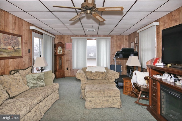 living room with wooden walls, carpet floors, and ceiling fan