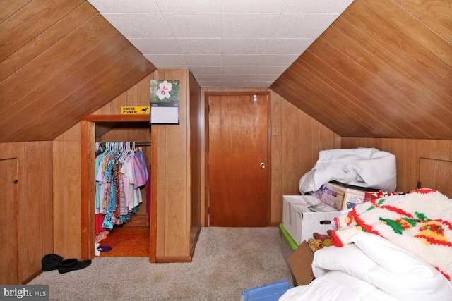 bedroom with carpet flooring, vaulted ceiling, a closet, and wood walls