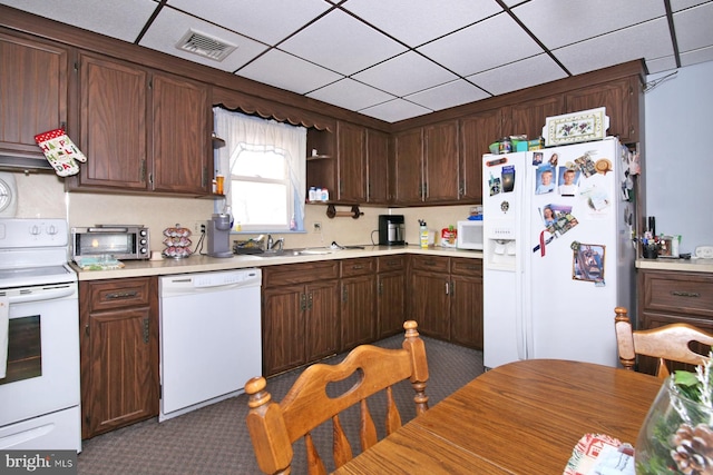 kitchen with dark brown cabinets, sink, dark carpet, and white appliances