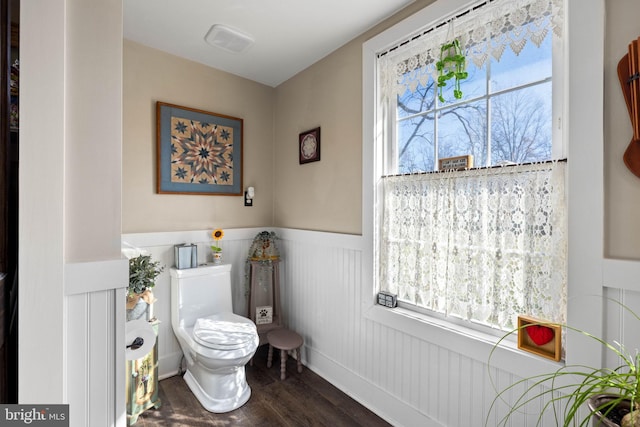 bathroom with toilet, wood-type flooring, and a healthy amount of sunlight