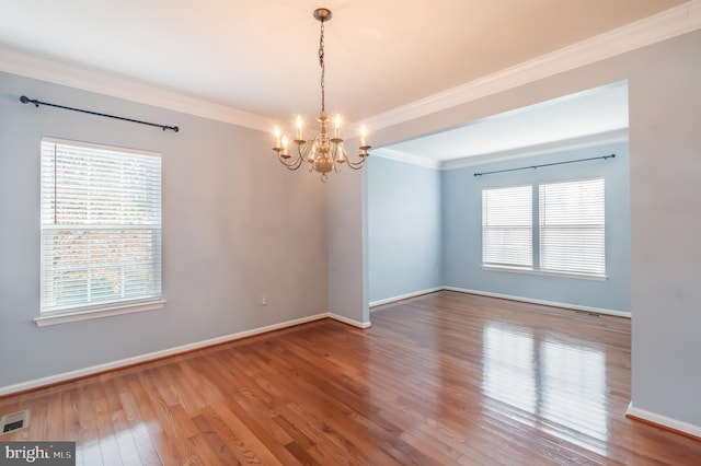 spare room featuring an inviting chandelier, hardwood / wood-style flooring, and crown molding