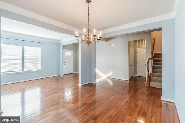 spare room with wood-type flooring, an inviting chandelier, and crown molding