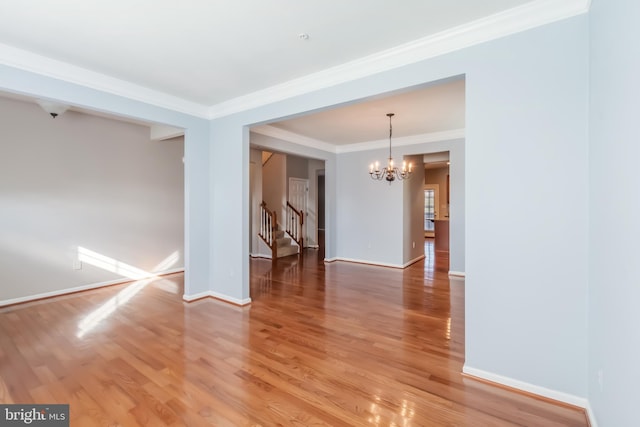 empty room featuring ornamental molding, hardwood / wood-style floors, and an inviting chandelier