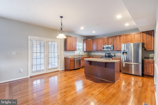 kitchen featuring stainless steel appliances, light hardwood / wood-style floors, hanging light fixtures, sink, and a kitchen island