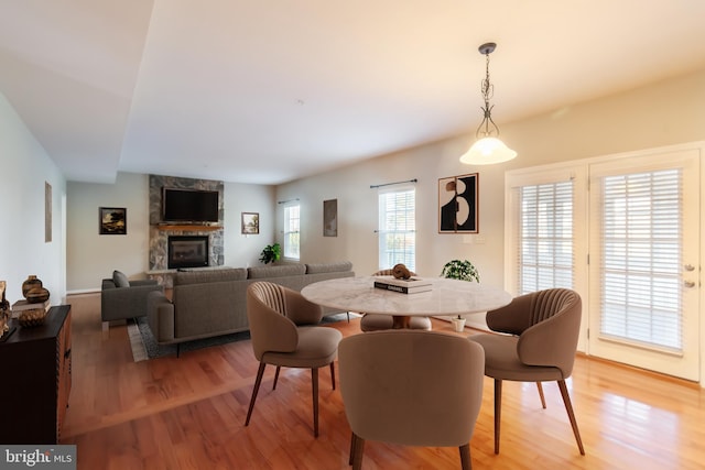 dining area featuring a stone fireplace, hardwood / wood-style floors, and plenty of natural light