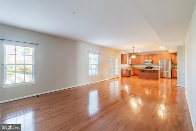 unfurnished living room with light hardwood / wood-style floors and a healthy amount of sunlight