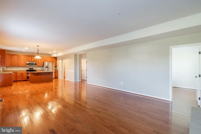 unfurnished living room with sink and light hardwood / wood-style flooring