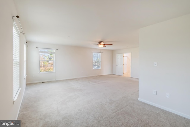 empty room featuring plenty of natural light, ceiling fan, and light colored carpet