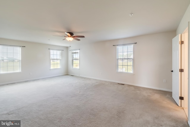 carpeted empty room with ceiling fan and a healthy amount of sunlight