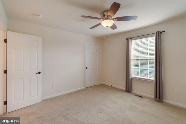 empty room with ceiling fan and light carpet