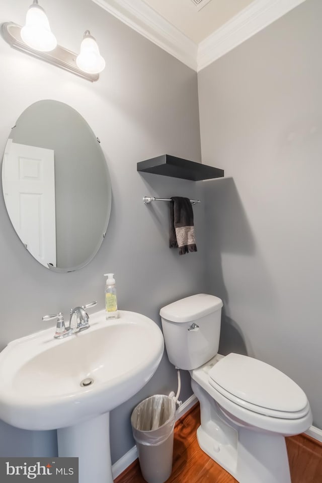 bathroom featuring toilet, sink, hardwood / wood-style flooring, and ornamental molding