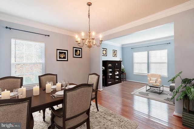 dining room with hardwood / wood-style flooring, crown molding, and a notable chandelier