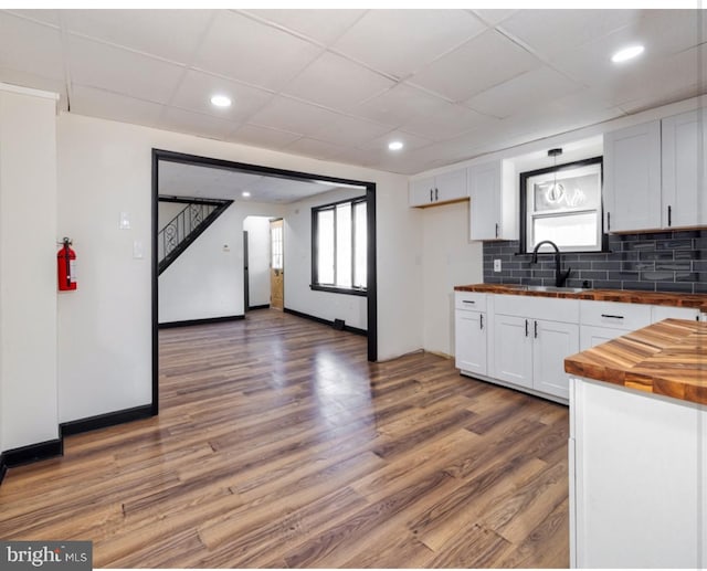 kitchen with dark wood-type flooring, wooden counters, white cabinets, sink, and tasteful backsplash