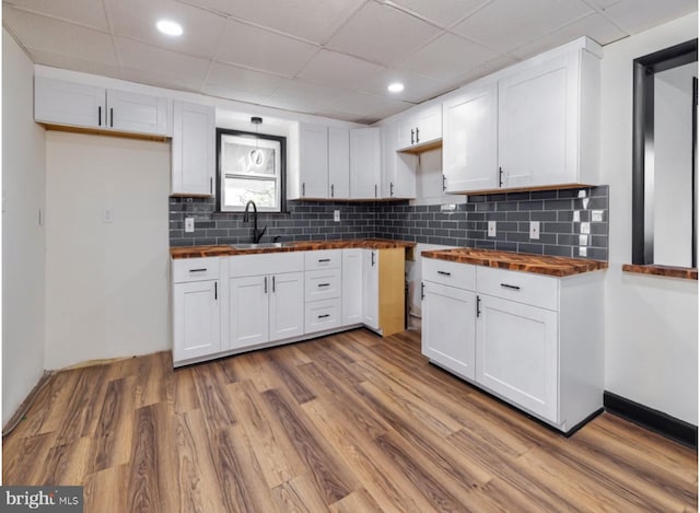 kitchen featuring white cabinetry, sink, wood-type flooring, and wood counters