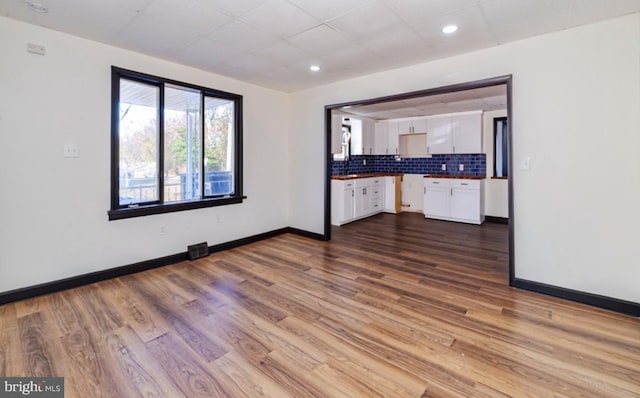 kitchen featuring white cabinets, hardwood / wood-style flooring, and tasteful backsplash