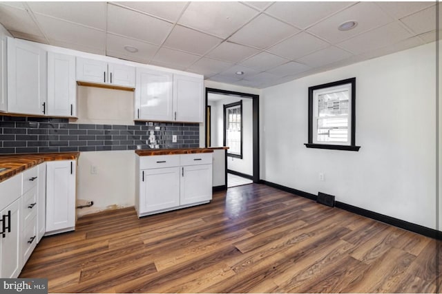 kitchen with tasteful backsplash, butcher block counters, white cabinetry, and dark hardwood / wood-style floors