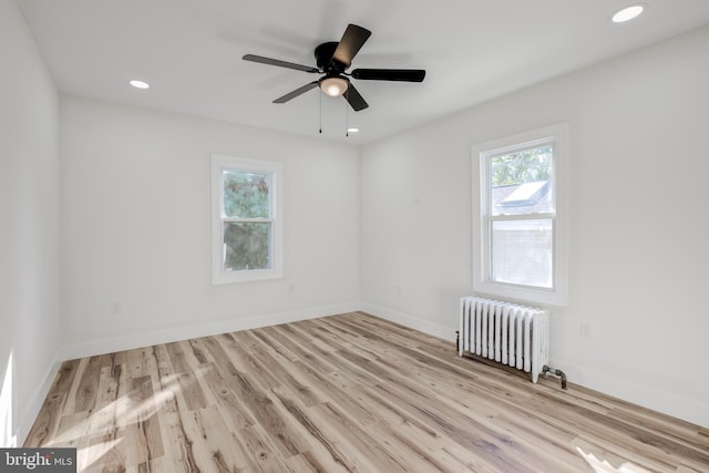 unfurnished room with radiator heating unit, light hardwood / wood-style floors, and ceiling fan