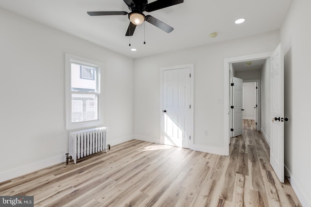 unfurnished bedroom featuring light wood-type flooring, radiator heating unit, and ceiling fan