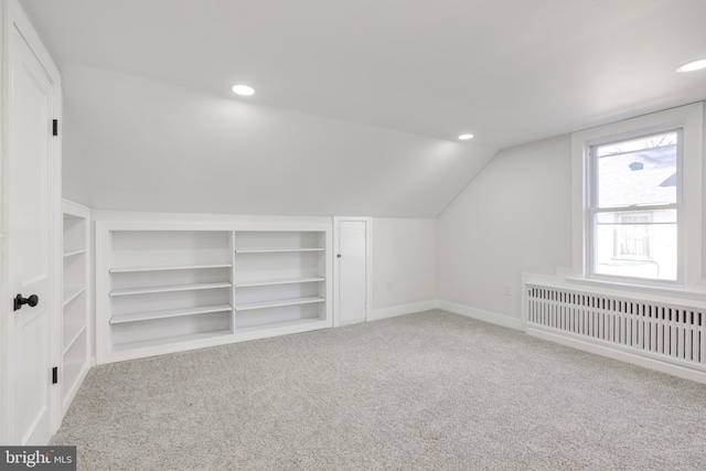 additional living space featuring radiator, lofted ceiling, and carpet floors