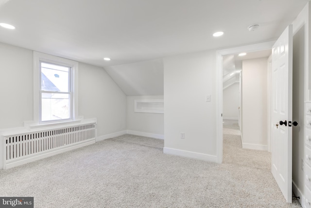 bonus room with radiator heating unit, lofted ceiling, and light colored carpet