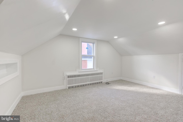 bonus room featuring built in shelves, radiator, vaulted ceiling, and carpet floors