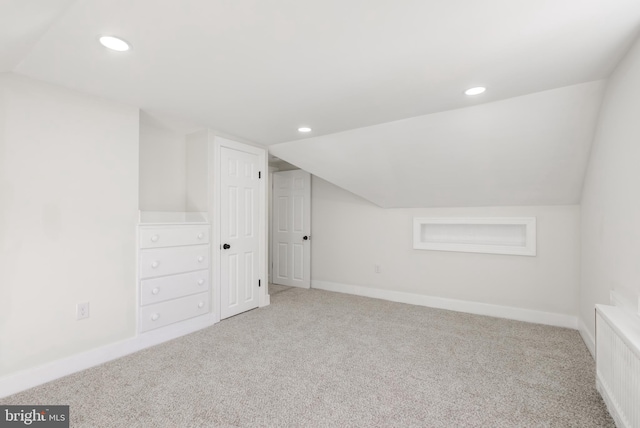 additional living space with radiator, lofted ceiling, and carpet floors