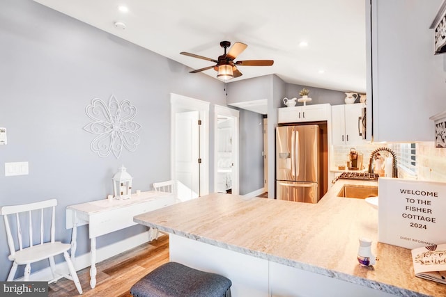 kitchen featuring white cabinets, stainless steel refrigerator with ice dispenser, kitchen peninsula, sink, and light hardwood / wood-style flooring