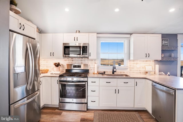 kitchen with white cabinetry, sink, appliances with stainless steel finishes, backsplash, and wood-type flooring