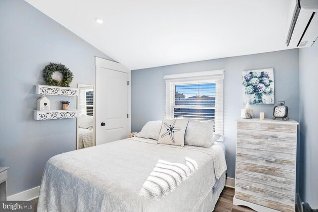 bedroom featuring dark wood-type flooring, lofted ceiling, and a wall mounted air conditioner