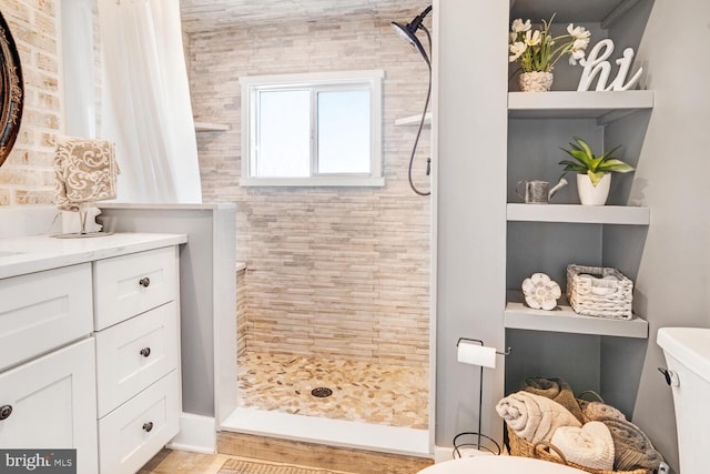 bathroom with vanity, toilet, and tiled shower