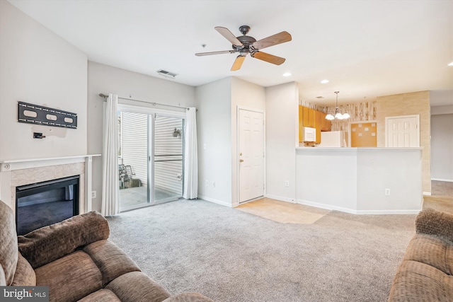 living room with light carpet, a fireplace, and ceiling fan with notable chandelier