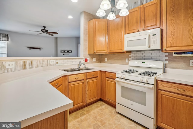 kitchen featuring white appliances, backsplash, ceiling fan with notable chandelier, sink, and kitchen peninsula