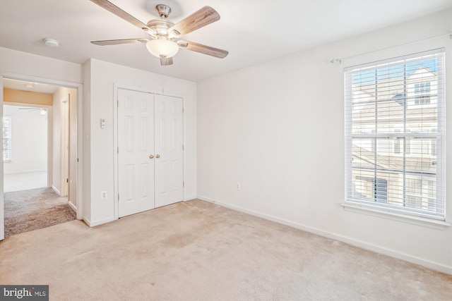 unfurnished bedroom with a closet, light colored carpet, and ceiling fan