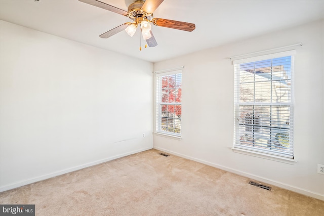 spare room with a wealth of natural light, ceiling fan, and light carpet