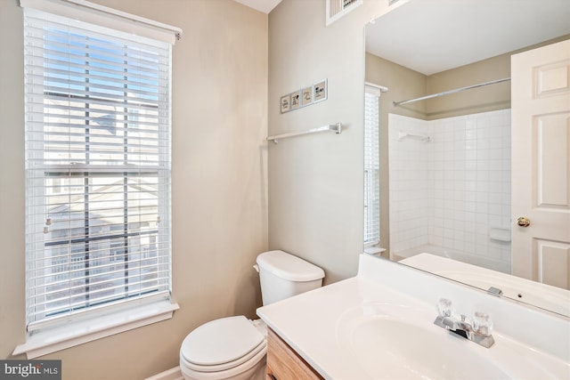 bathroom featuring vanity, toilet, and a tile shower