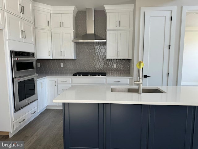 kitchen with stainless steel double oven, black gas cooktop, dark hardwood / wood-style floors, white cabinets, and wall chimney exhaust hood