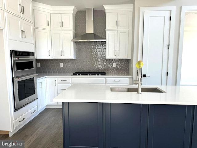 kitchen featuring stainless steel double oven, black gas cooktop, white cabinets, dark wood-type flooring, and wall chimney exhaust hood