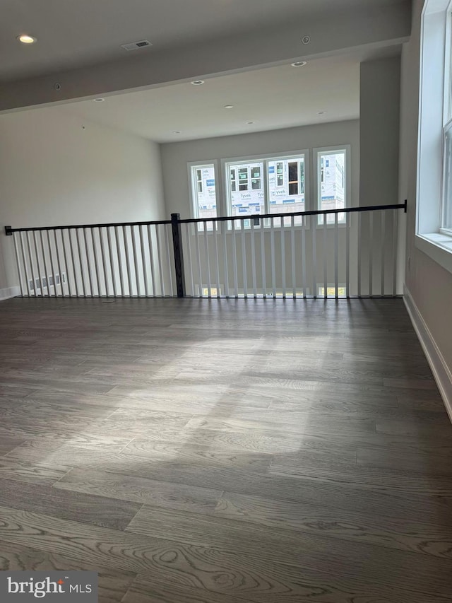 spare room featuring beamed ceiling, hardwood / wood-style flooring, and plenty of natural light