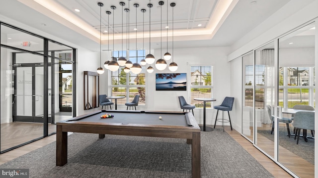 game room featuring wood-type flooring, plenty of natural light, a raised ceiling, and billiards