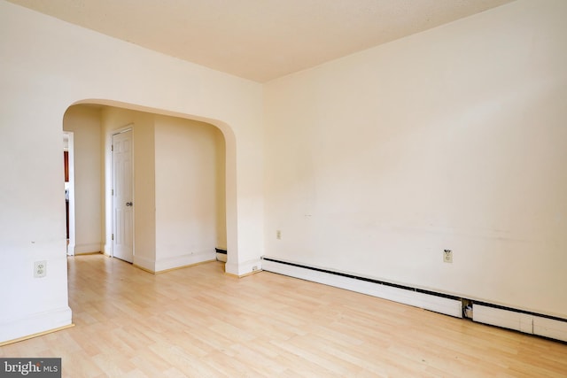 empty room with light wood-type flooring and a baseboard radiator