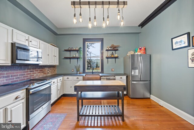 kitchen with appliances with stainless steel finishes, light wood-type flooring, white cabinetry, and hanging light fixtures